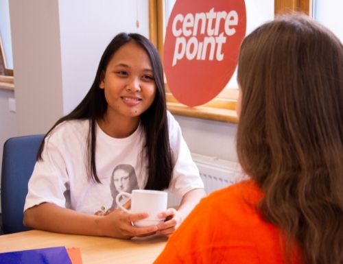 Volunteer chats with service user with a coffee at Centrepoint